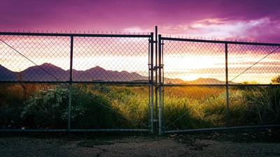 a fence with mountains in the background at sunset